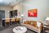 Chic apartment interior showcasing an elegant open-plan living area with a modern kitchen, stylish seating, and vibrant artwork.