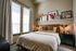 Charming bedroom with a cozy bed, stylish decor, and natural light from large windows.