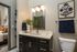 Contemporary bathroom with sleek dark cabinetry, a stylish mirror, elegant wall art, and vibrant floral arrangement, offering a touch of luxury and modern living.
