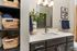 Chic bathroom featuring modern vanity with sleek faucet, elegant mirror, and vibrant decor accents, complemented by spacious storage baskets.