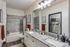 Modern and elegant bathroom showcasing a spacious granite countertop with double sinks, sleek lighting, and stylish gray tile accents.