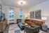 Elegant living room with modern decor, featuring a sleek brown sofa, stylish armchairs, and contemporary artwork on the walls.