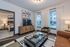 Chic living room with modern decor, large windows, and a cozy bedroom view, offering natural light and stylish comfort.