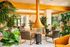 Luxurious lounge interior with modern armchairs, central copper fireplace, and lush greenery, creating a serene oasis atmosphere.