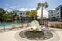 Luxurious apartment complex with stunning poolside area, palm trees, and a unique glass orb water feature.