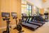 Modern fitness center with state-of-the-art equipment, including treadmills and stationary bikes, surrounded by stylish wooden paneling and large windows.
