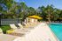 Luxurious outdoor swimming pool with elegant loungers and vibrant yellow umbrellas, surrounded by lush greenery for a serene retreat.
