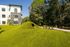 Modern apartment exterior with lush green landscape, featuring a unique geometric play structure and inviting outdoor area.