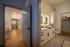 Modern apartment hallway leading to a cozy bathroom with elegant lighting and sleek cabinetry, showcasing a seamless blend of wood and tile flooring.