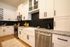 Modern kitchen with sleek white cabinets, granite countertops, black hexagonal backsplash, and stainless steel appliances. Inviting and stylish, perfect for culinary enthusiasts.
