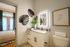 Modern bathroom with sleek granite countertop, illuminated mirror, and stylish botanical decor. Warm, inviting bedroom in the background.