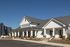 Charming modern apartment complex exterior with clean white siding and inviting front porch, bathed in sunlight under a clear blue sky.