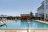 Luxurious outdoor pool area with inviting lounge chairs, elegant wooden pergola, and pristine landscaping under a clear sky.