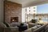 Charming outdoor patio featuring a cozy brick fireplace, stylish seating, and a view of a sparkling swimming pool.