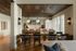 Elegant dining area with chic wooden ceiling, modern lighting, and a cozy workspace overlooking large windows.