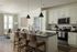 Chic apartment kitchen with modern white cabinetry, an inviting island with seating, and a cozy living area bathed in natural light.