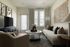 Inviting living room with modern decor, featuring a cozy sofa, stylish armchair, large TV, and decorative wall art.
