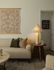 Cozy living room with a stylish beige couch, elegant table lamp, and decorative pillows against an artful wall hanging.