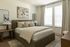 Inviting bedroom with a plush bed, modern decor, and natural light streaming through large windows, creating a cozy and elegant atmosphere.