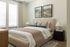 Cozy bedroom with elegant decor, featuring a plush bed, stylish artwork, and abundant natural light from large windows.