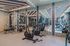 Modern apartment gym with cutting-edge exercise equipment, including weights, stationary bikes, and treadmills, in a sleek mirrored space.