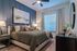 Elegant bedroom with a modern design, featuring a plush bed, abstract artwork, and stylish decor, offering a serene and inviting atmosphere.