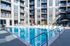 Luxurious apartment complex with a stunning outdoor pool, sleek lounge chairs, and contemporary architecture.