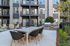 Modern apartment courtyard with elegant outdoor dining area, stylish patio seating, and sleek barbecue grill, ideal for social gatherings.
