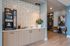 Chic modern lounge featuring a coffee station with sleek cabinetry, elegant geometric wall tile, stylish seating, and contemporary decor.