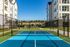 Modern apartment complex with a vibrant blue tennis court, perfect for recreational activities amidst stylish architecture.