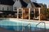Luxurious outdoor pool area with elegant wooden cabanas and chic seating, perfect for relaxation and entertaining.