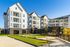 Modern apartment building with stylish balconies and well-maintained green spaces under a clear blue sky.