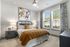 Two-Bedroom Apartments in Birmingham, AL - Tributary Rise - Bedroom with Carpet Flooring, Bed, Nightstands with Lamps, Wall Art, Windows with Blinds and Curtains, Ceiling Fan, and Dresser.