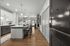 Modern apartment entryway leading to a chic kitchen with a large island, stylish pendant lighting, and an inviting dining area. Bright, open-concept design with elegant finishes.