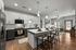 Modern open-concept kitchen and living area with sleek appliances, stylish island seating, and bright natural lighting.