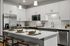 Modern kitchen with sleek white cabinets, spacious island with seating, and stainless steel appliances, creating an inviting and stylish cooking space.