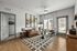 Chic living room with modern decor, featuring a plush leather sofa, elegant armchairs, and large windows offering abundant natural light.