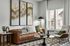 Cozy and inviting living room with a luxurious leather sofa, elegant modern armchair, abstract wall art, and ample natural light from large windows.