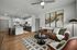 Chic apartment living room with stylish leather sofa, modern art, and open kitchen design featuring contemporary lighting and sleek appliances.