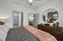 Cozy bedroom with elegant decor, featuring a comfy bed, stylish mirror, and a glimpse into a modern kitchen.