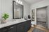 Modern bathroom featuring a sleek gray vanity, elegant countertop with a chic plant, and a spacious walk-in closet.