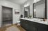 Elegant and modern bathroom with dual sinks, stylish dark cabinetry, and a spacious walk-in closet.