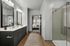 Elegant bathroom with dual sinks, large mirrors, and a stylish glass shower adjacent to a cozy bedroom view, perfect blend of modern design and comfort.
