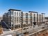 Modern apartment complex with sleek design, large windows, and balconies, situated in a vibrant urban setting.