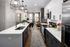 Modern apartment kitchen with sleek countertops, elegant lighting, and cozy living area in the background.