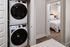 Chic apartment feature with modern stacked washer and dryer next to a cozy bedroom illuminated by natural light.