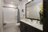 Elegant bathroom featuring modern fixtures, a spacious vanity, and luxurious shower with tiled walls, complemented by stylish decor and vibrant accent plant.