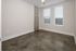 Modern minimalist room with polished concrete floors and bright natural light from two large windows.