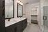 Elegant modern bathroom featuring dual sinks, large mirrors, and a sleek walk-in shower with glass doors, leading to a spacious walk-in closet.