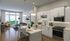 Modern open-concept kitchen and living area with sleek cabinetry, elegant lighting, and floor-to-ceiling windows offering a lush green view.